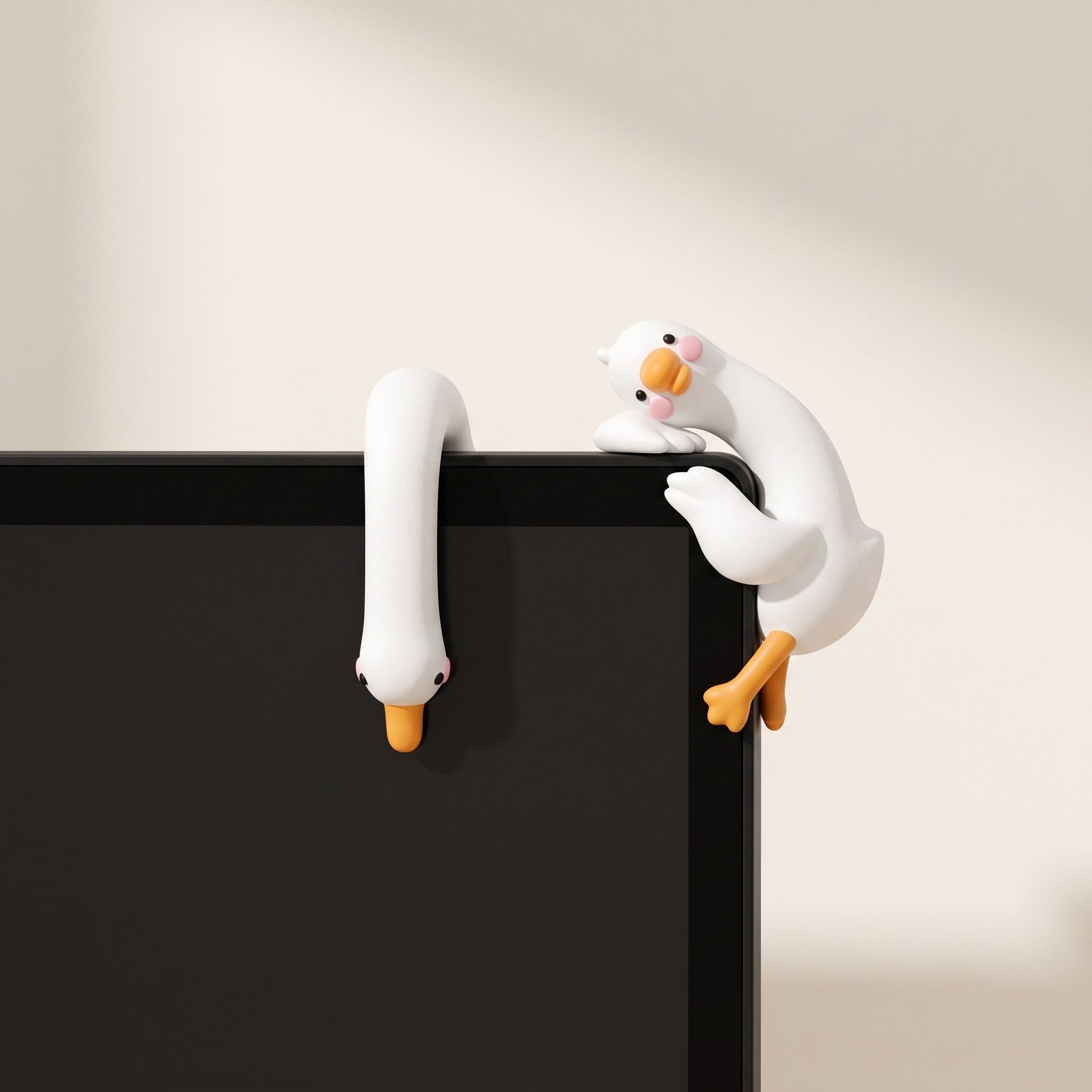 A detailed close-up lifestyle image of two white resin mini duck figurines in Dangling and Climbing poses perched creatively on the top corner of a black computer monitor