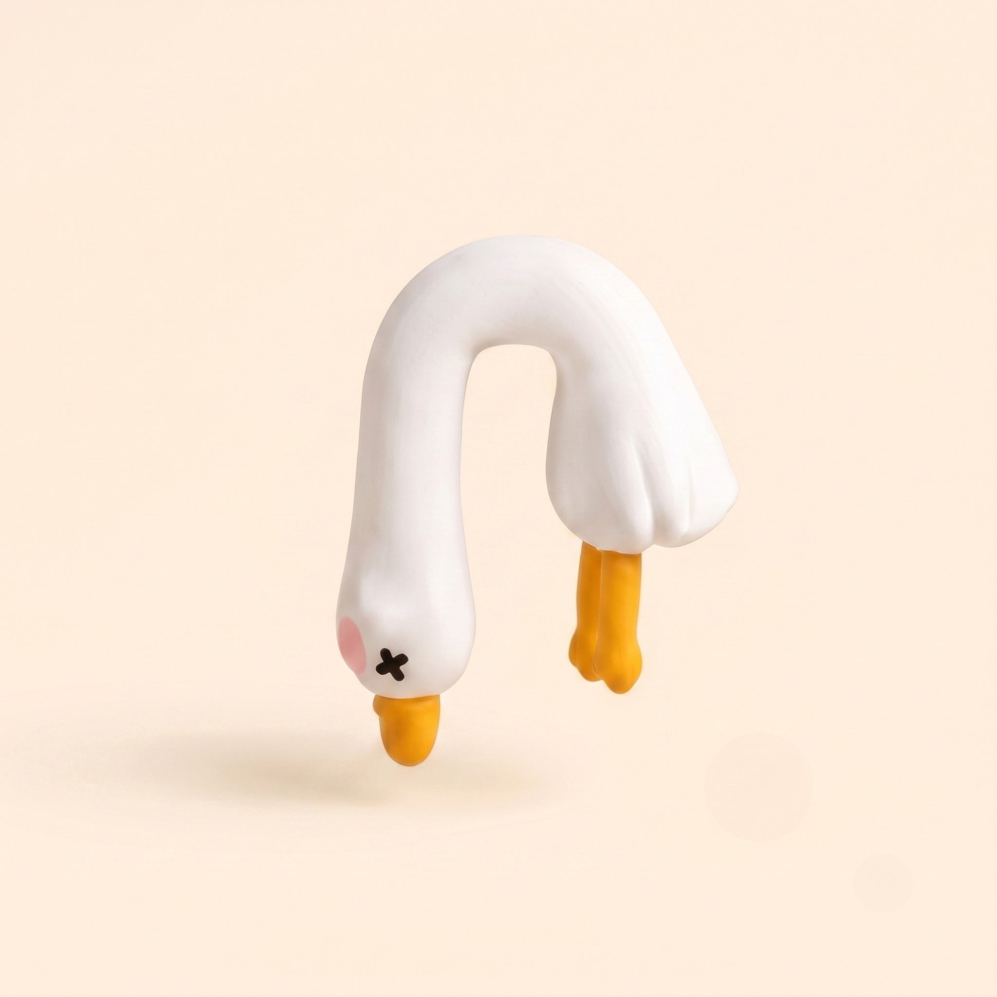 A studio product shot of the By1994 mini duck figurine in the Dangling pose, featuring an upside-down hanging white resin duck with X-eyes and yellow feet on a cream backdrop.