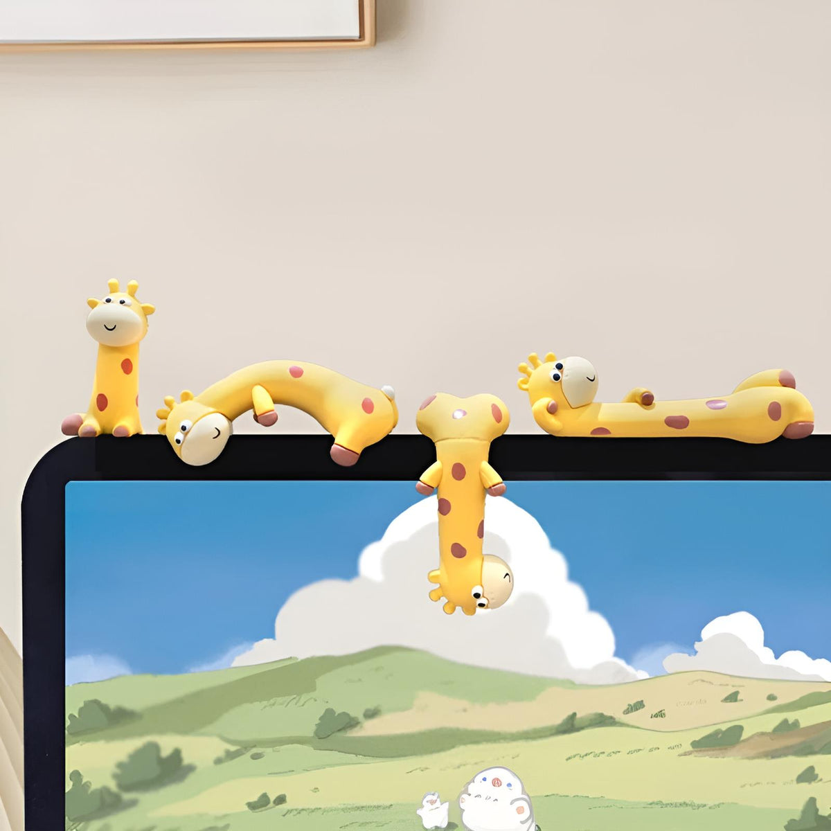 A bright desktop lifestyle shot featuring all four By1994 mini giraffe figures perched playfully along the upper edge of a computer monitor displaying a scenic landscape.