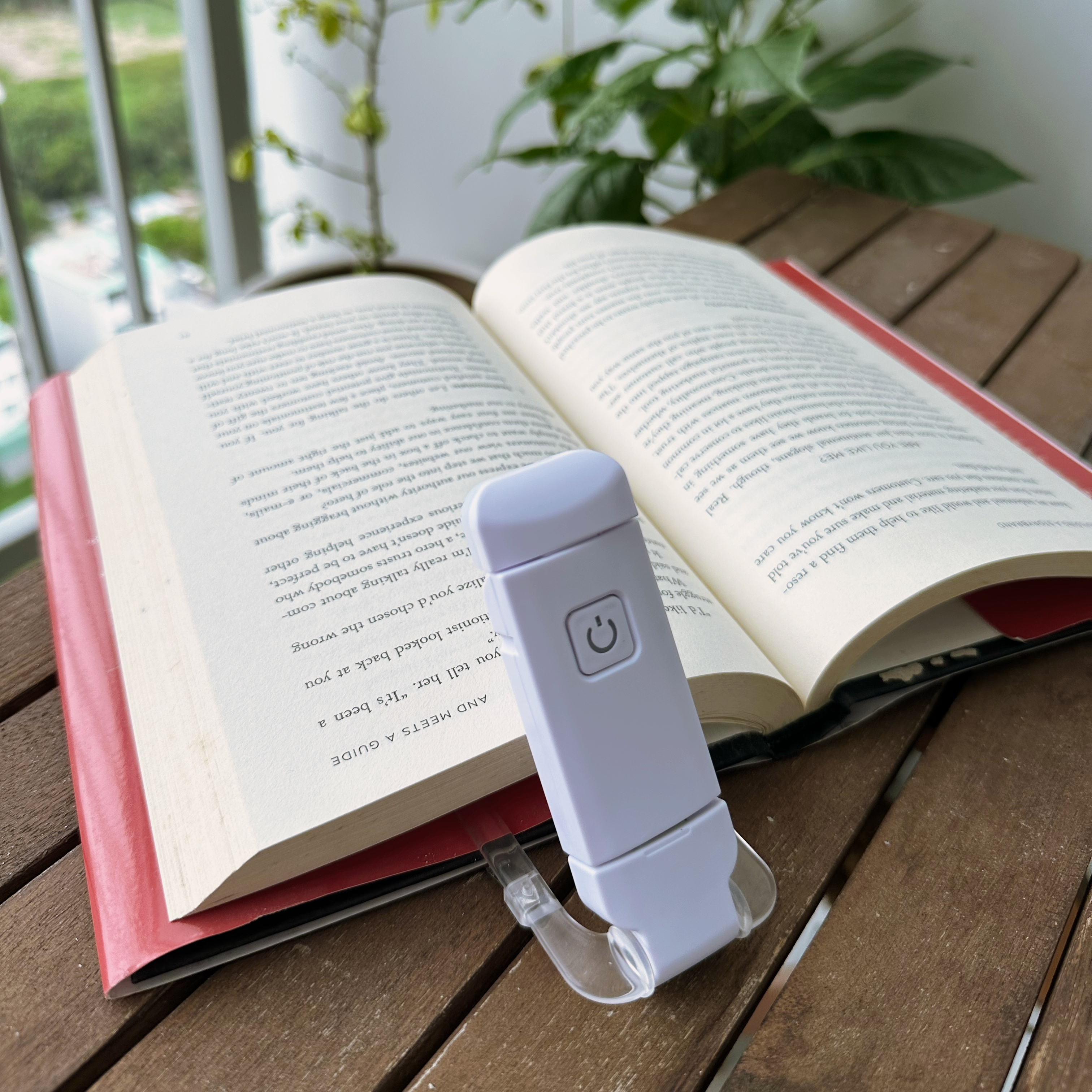 A bright morning lifestyle shot of the minimalist clip-on reading light attached to a notebook on a light wooden desk, beautifully bathed in soft natural morning sunlight near a quiet corner.