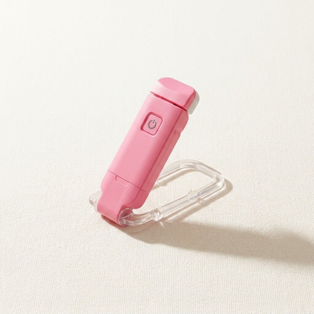 A crisp lifestyle hero image showcasing a pink portable LED book light arranged beautifully on a clean canvas cream background.