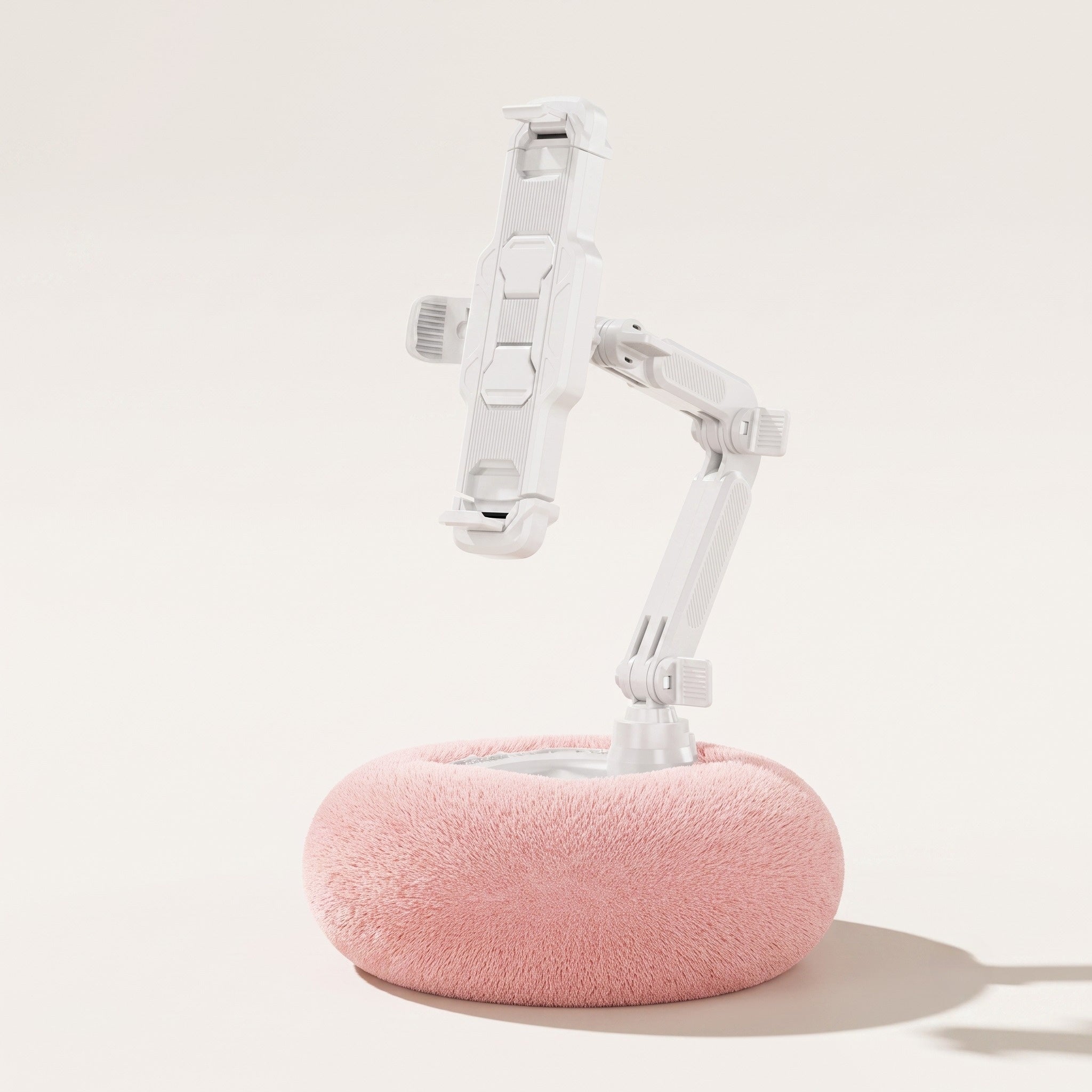 A studio product view of the By1994 large plush pillow tablet stand in Soft Pink, showcasing the expanded tablet mount bracket and white adjustable arm on a clean cream background.